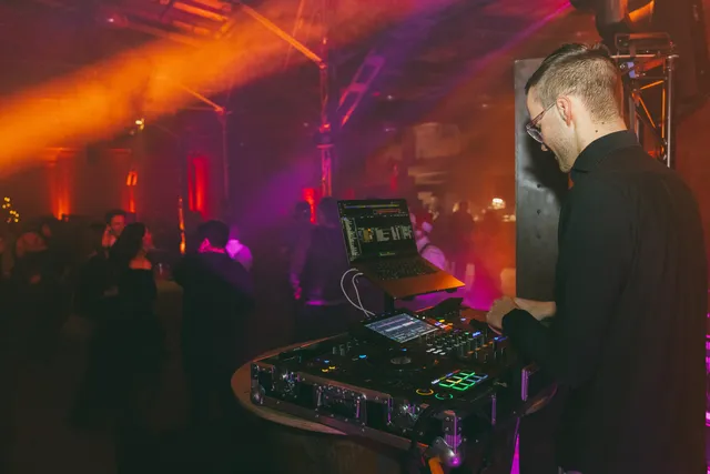 DJ Moritz am Pult, hinter ihm Lichtshow und Tanzfläche