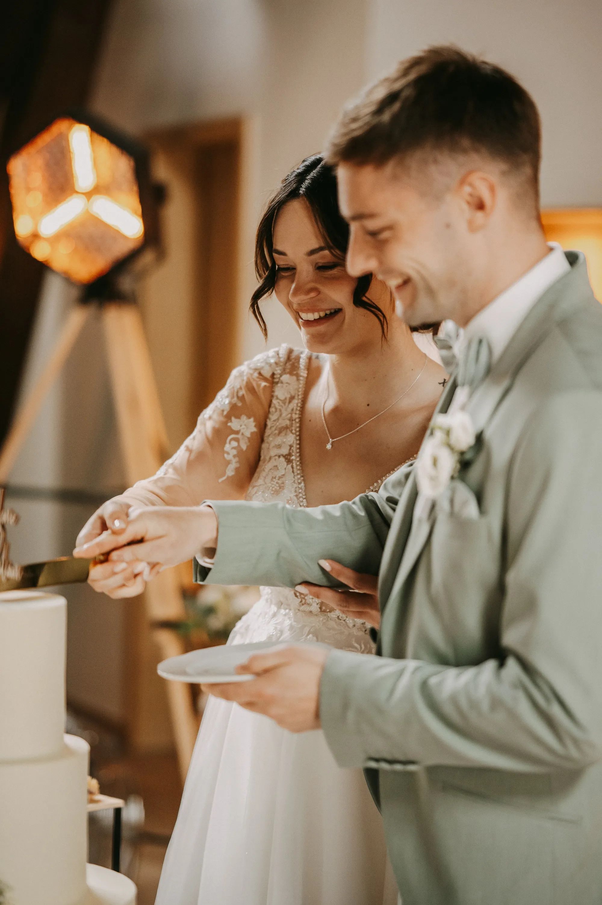 Brautpaar lacht beim Anschneiden der Hochzeitstorte