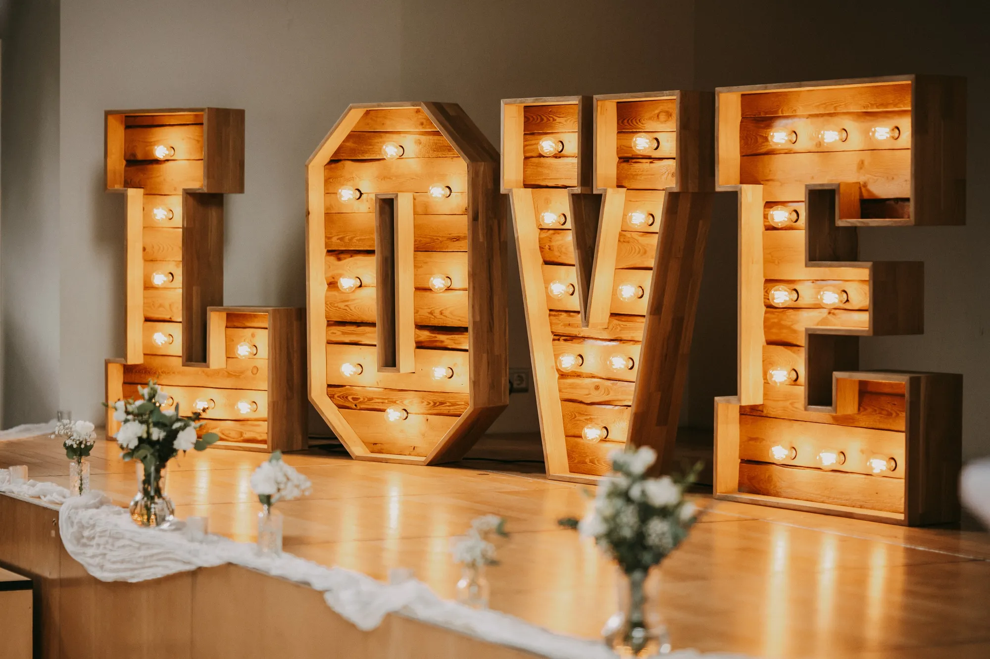 XXL LOVE-Buchstaben leuchten vor einer festlich gedeckten Hochzeitstafel