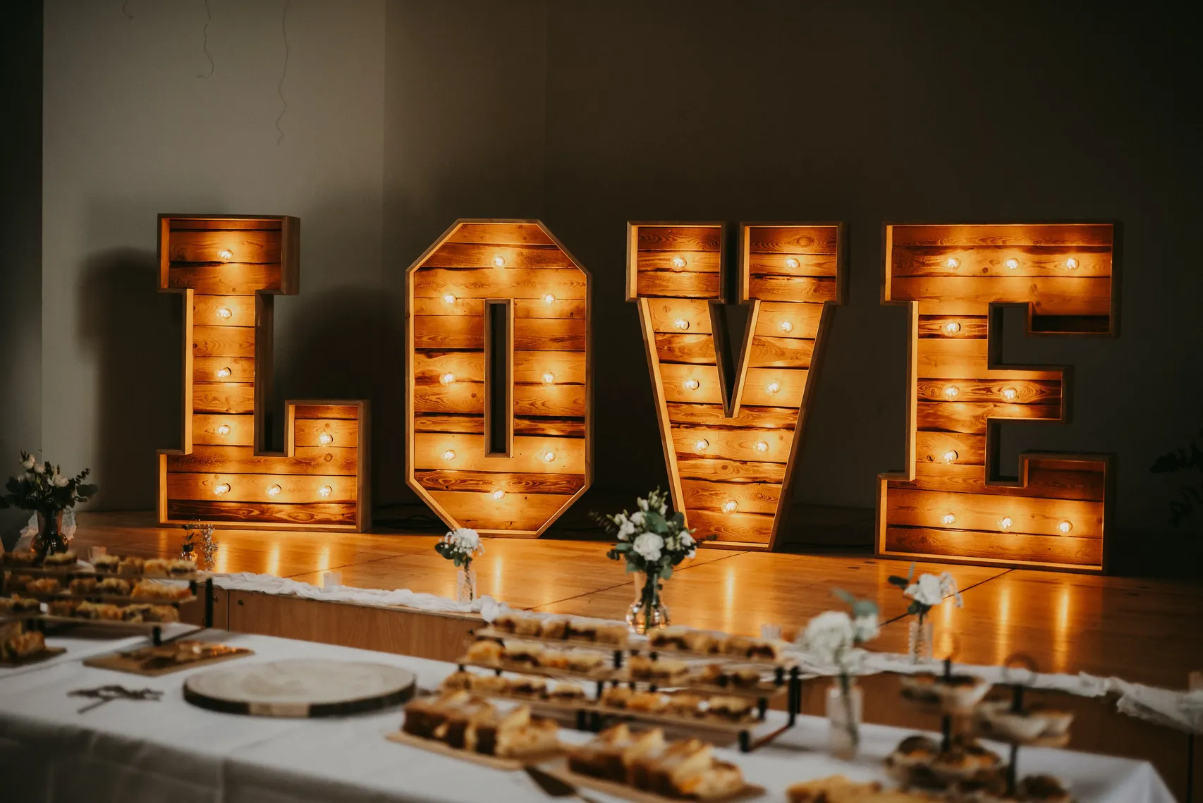 Leuchtende XXL LOVE-Buchstaben mit Glühbirnen vor einer gedeckten Hochzeitstafel